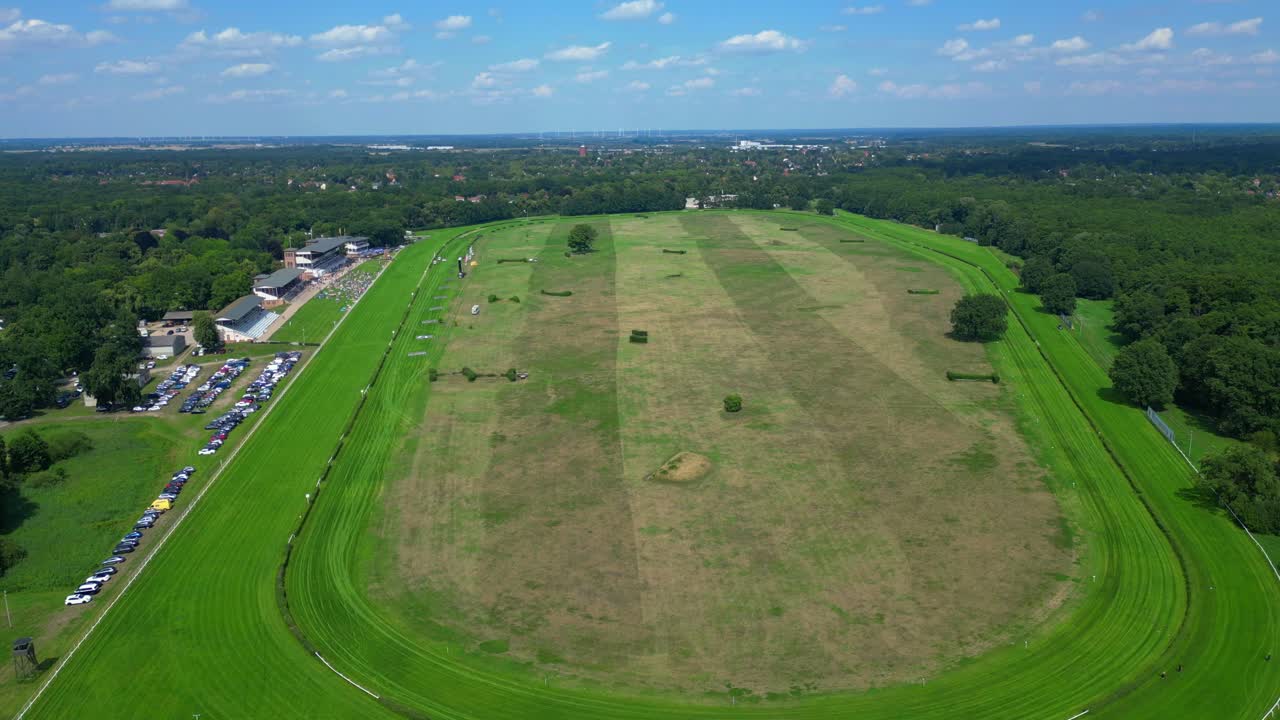 Horse gallop racecourse near a forest in Germany, parking lot visible. Best aerial view flight ascending drone