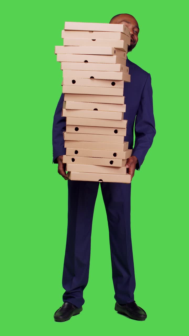 Video verticale: vista frontale di un imprenditore che tiene in mano una grande pila di cartoni della pizza