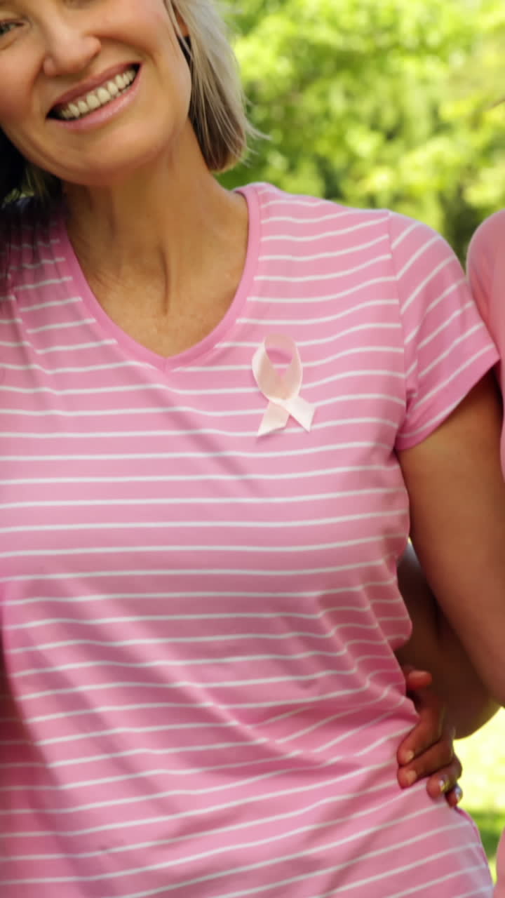 mujeres sonrientes vestidas de rosa para concientizar sobre el cáncer de mama en el parque