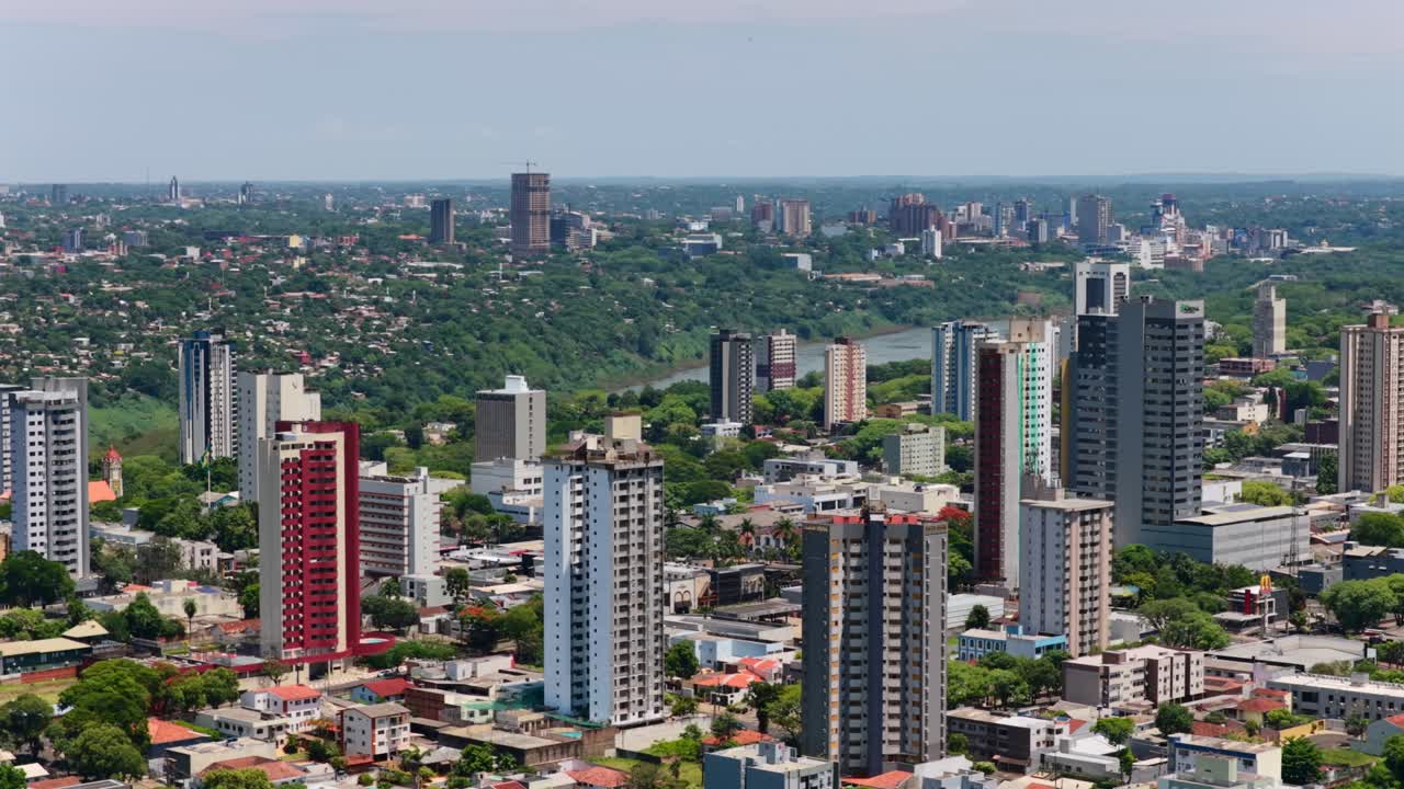 Skyline urbana di Foz do Iguaçu con alti edifici in primo piano e Ciudad del Este visibile in lontananza al di là del fiume Paraná