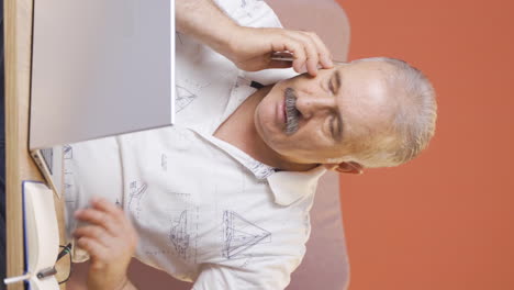 Vertical-video-of-Old-man-working-hard-on-laptop.