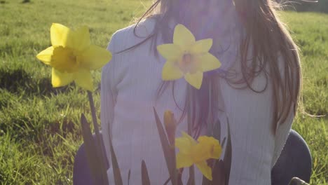 Carefree-Woman-relaxing-in-meadow-with-daffodils
