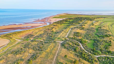 discover the idyllic charm of a golden hour coastal scene through breathtaking aerial drone footage: estuary, sandbanks, ocean, and marshlands