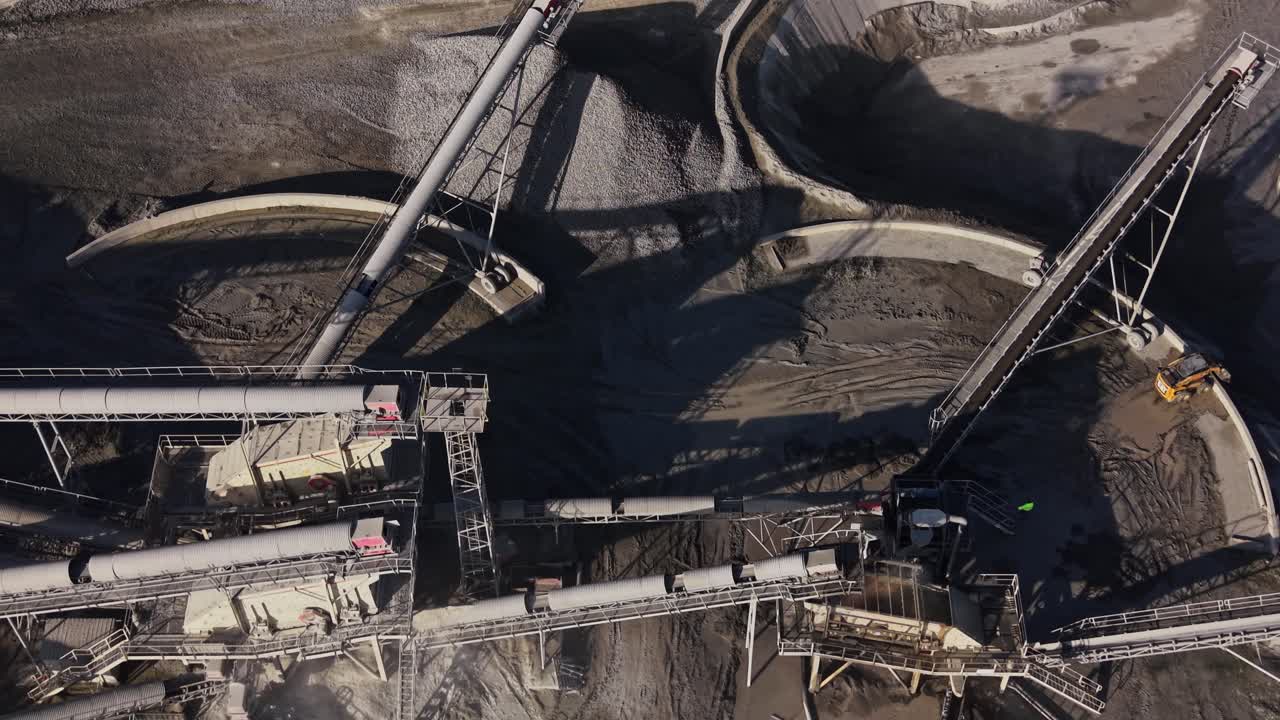 Heavy machinery operates in a busy mining site during daylight hours