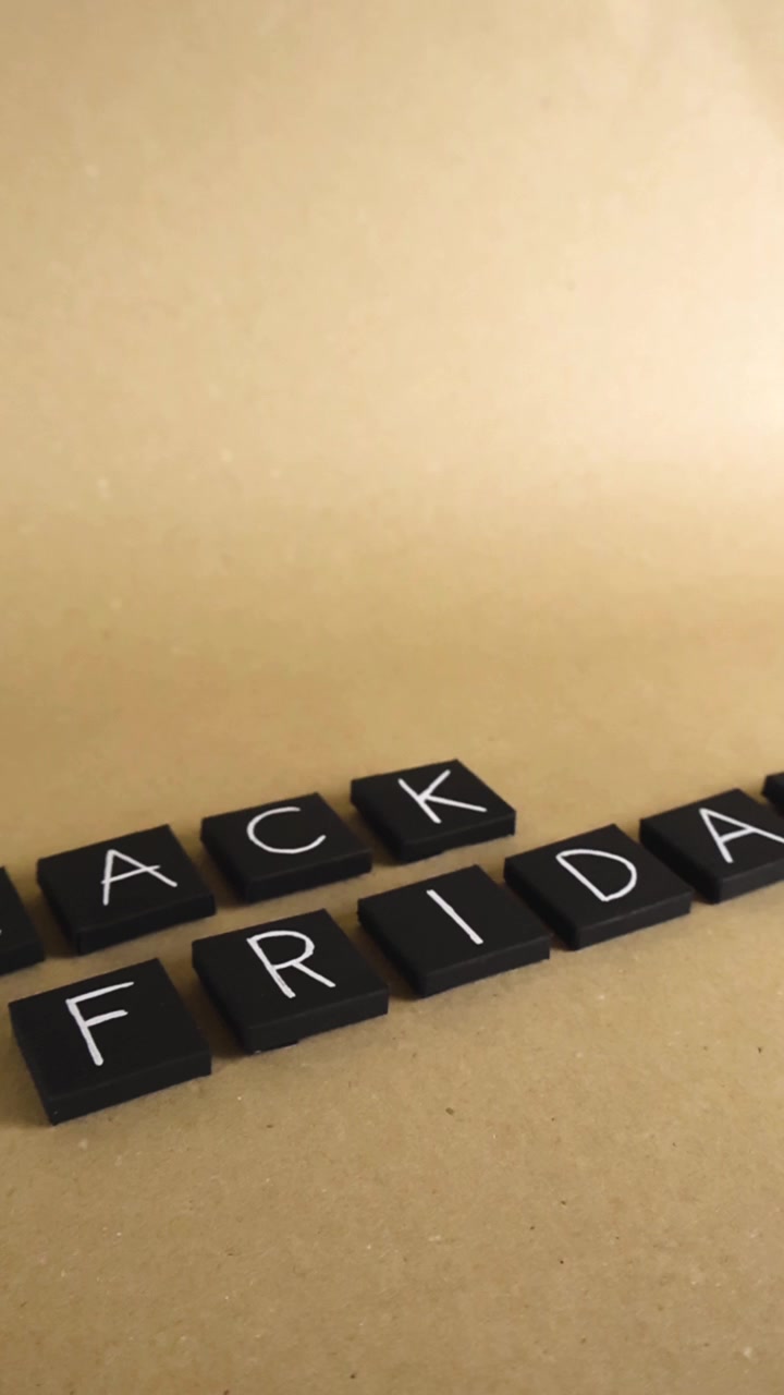 Piastrelle di carta nera fatte a mano che compongono le parole Black Friday che scivolano su uno sfondo marrone chiaro, ideali per creare pubblicità e storie per i social media per il famoso evento di shopping