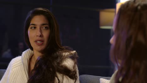 dos amigas sentadas en el sofá en casa o en un bar o café hablando juntas 1