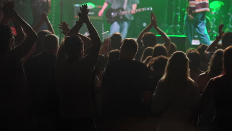 audience cheering at a live concert with vibrant lights and energetic atmosphere in the background