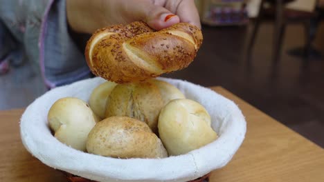 woman picking up a bread roll from a bread basket