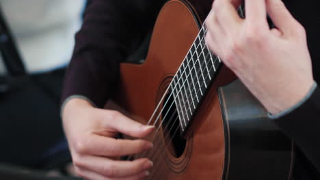 detalle de una guitarra clásica y manos masculinas jugando en ella