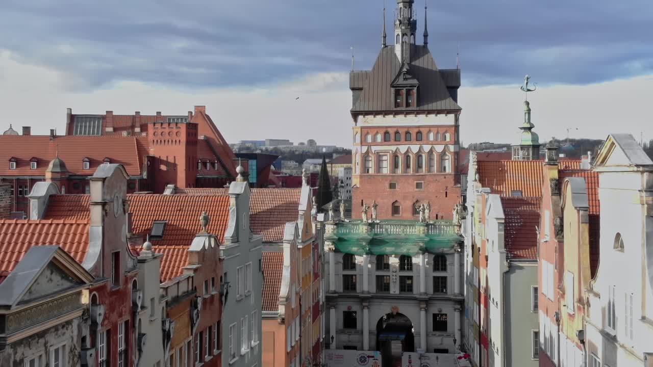 Vista di una strada di Danzica con edifici storici e persone che camminano sotto.