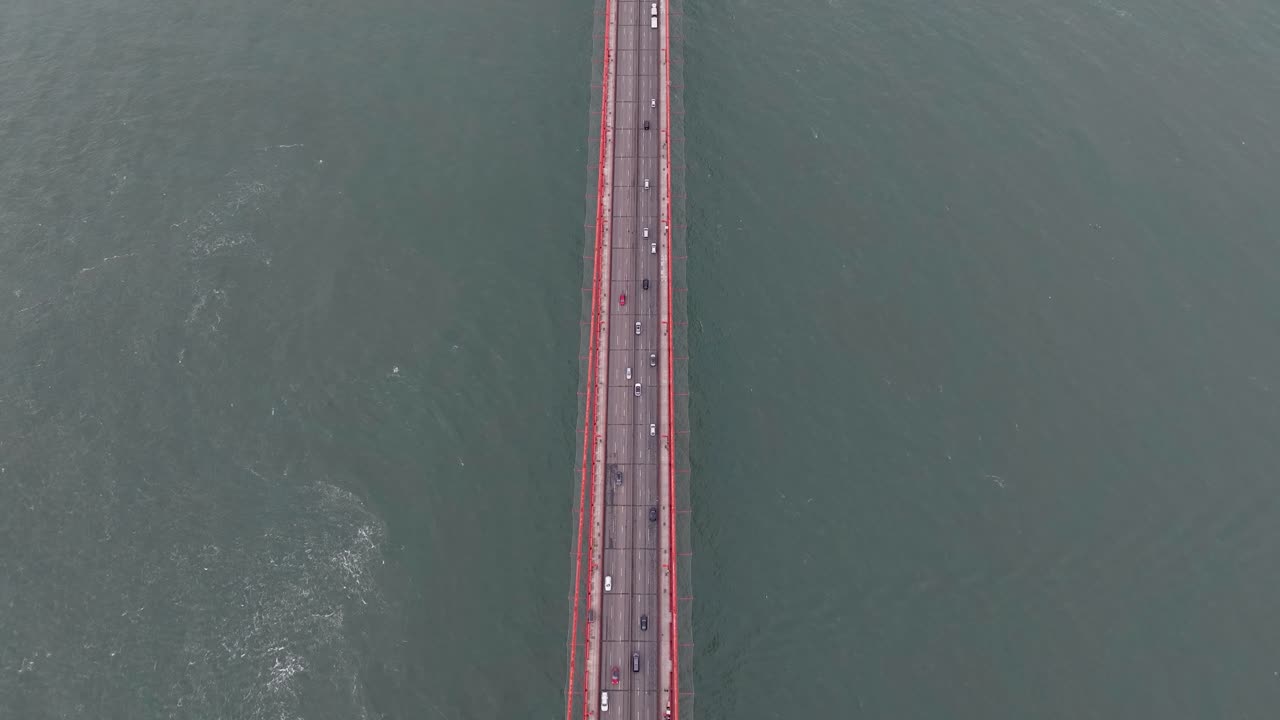 Aerial follows motorway on Golden Gate Bridge and tilts up toward Battery Ridge
