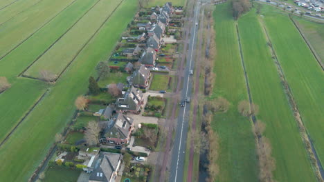 Antenne-Von-Autos,-Die-über-Eine-Ruhige-Straße-Fahren,-Die-Neben-Einer-Reihe-Von-Freistehenden-Häusern-In-Einer-Ländlichen-Gegend-Liegt