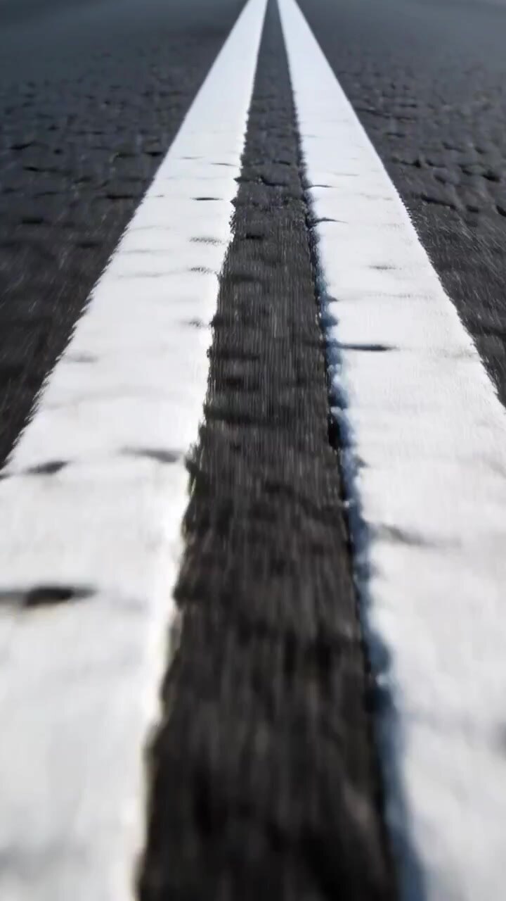 Video verticale: Operatore che cammina, telecamera che segue linee bianche parallele sull'asfalto, ispezionando una giuntura.