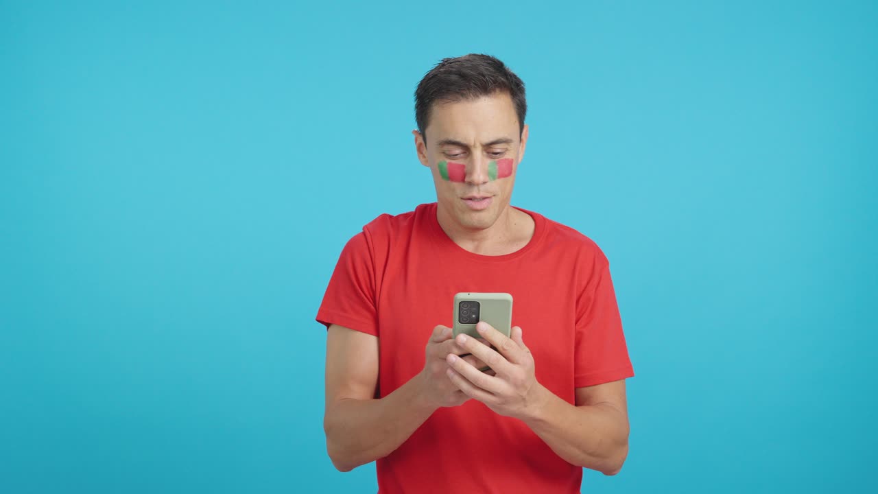 Portuguese supporter looking at his mobile smiling and showing it