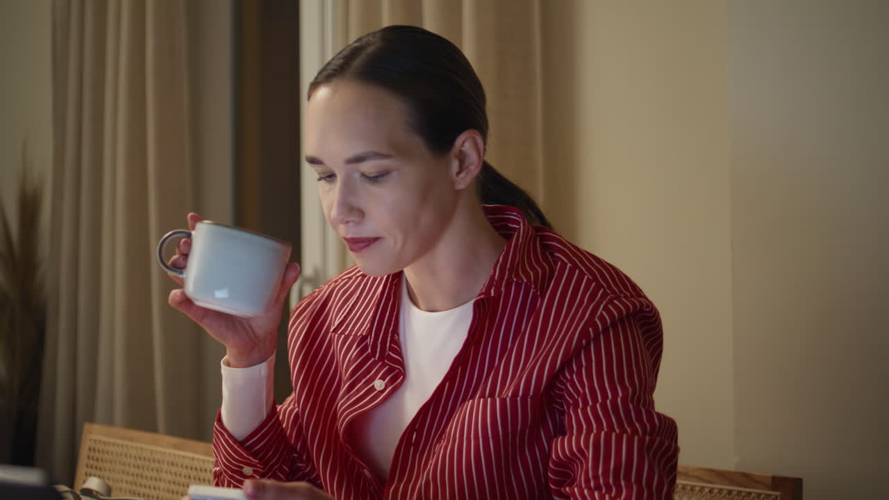 Woman multitasking laptop smartphone in late home office. Closeup freelancer sip