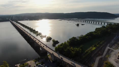 Absteigende-Drohnenaufnahme-Der-Veteranen-Gedenkbrücke-Route-462-Bei-Sonnenuntergang-Mit-Der-Route-30-In-Der-Ferne,-York-County,-Pennsylvania-Am-Horizont