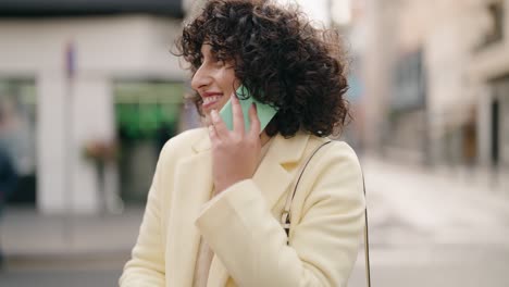 young woman smiling confident talking on the smartphone at street