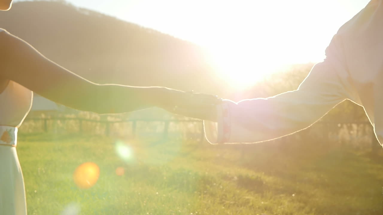Couple Holding Hands at Sunset in a Meadow