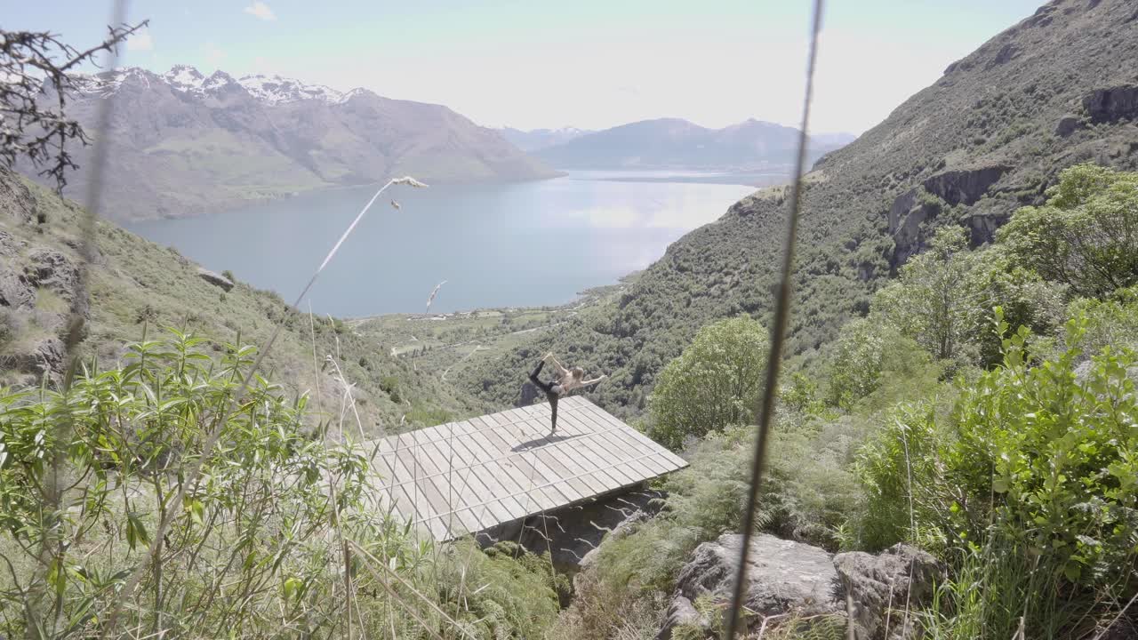 Girl performing yoga on a hot summer day overlooking blue lakes and mountain ranges in Queenstown New Zealand