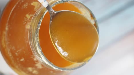 a spoonful of golden honey being lifted from a glass jar