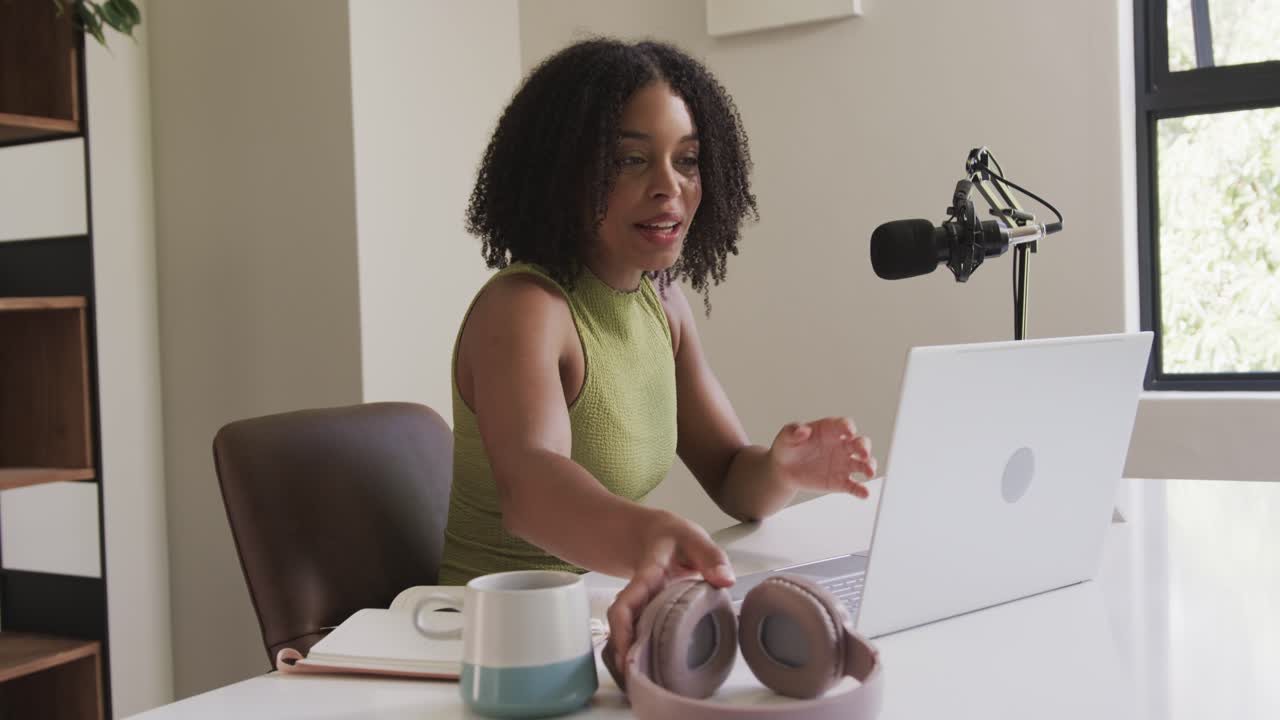 African American woman adjusting mic and testing placement then speaking, typing laptop for podcast