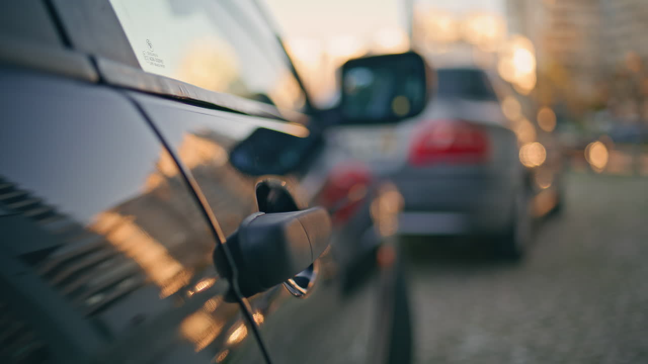 Man hand unlocking car door with dusk city backdrop closeup. Unknown guy opening
