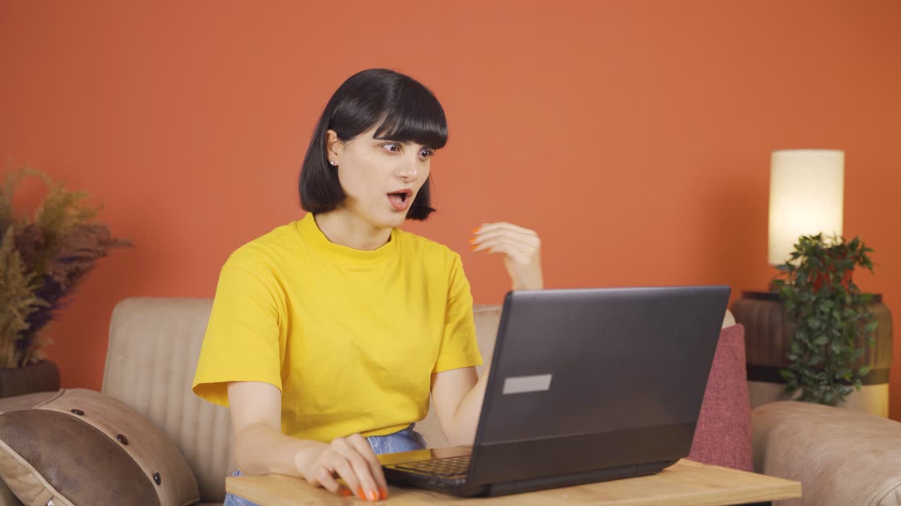 여성이 놀란 채로 노트북을 쳐다보고 있습니다.