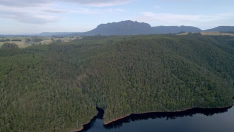 Abgelegener-Wald-Am-Lake-Barrington-Mit-Mount-Roland-Im-Hintergrund-In-Der-Nähe-Von-Sheffield,-Tasmanien,-Australien---Drohnenansicht