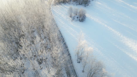 Luftaufnahme-Der-Verfolgung-Eines-Geländewagens-Auf-Der-Straße-Durch-Die-Verschneite-Landschaft