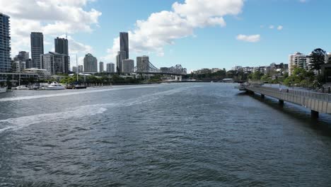 Volando-Junto-Al-Paseo-Fluvial-De-Brisbane-Hacia-El-Puente-De-La-Historia-Con-Brisbane-Al-Fondo