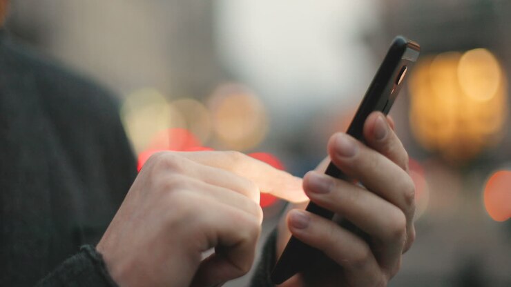 Close-up view of caucasian businessman hands texting on the phone in the street