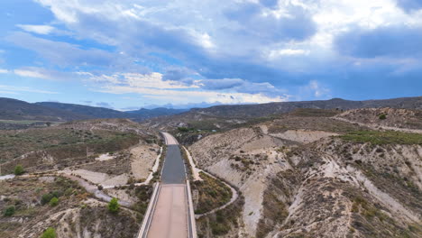 aerial hazily drifts above an extraordinary abandoned landscape bisected by a long empty road to nowhere, deep in almeria province andalusia spain