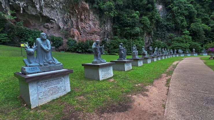 Statue di Buddha posizionate lungo il giardino esterno della grotta Kek Look Tong a Ipoh, Malesia - Panoramica a destra.