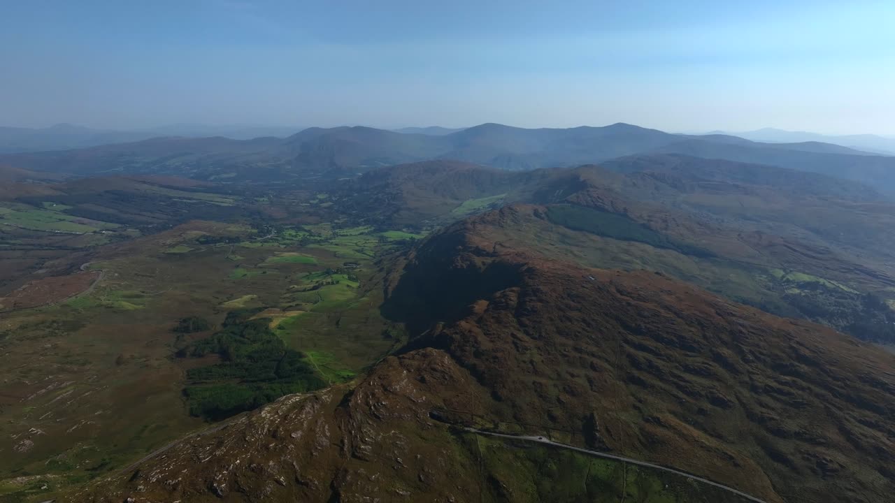 Caha Pass, County Cork, Ireland, September 2024. Drone pulls backwards in a panoramic overview and gradual descent offering a sweeping view of the mountain road along the border with County Kerry.