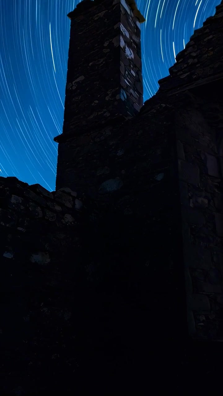 Video verticale: Telecamera in timelapse che riprende una torre di pietra e rovine di notte, con il timer che avvia le scie stellari.