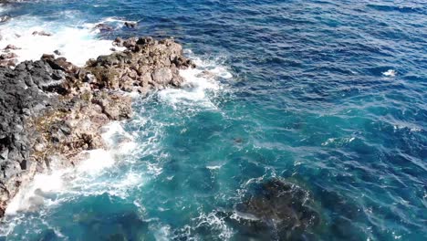 Flyover-of-an-outcrop-of-volcanic-rock-cliffs-and-pacific-ocean-waves