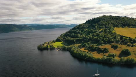 aerial drone shot over loch ness flying towards urquhart castle in the scottish highlands, scotland