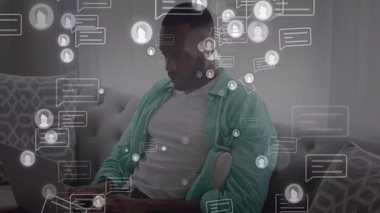 Animation of message and profile icons, african american man sitting on sofa and working on computer