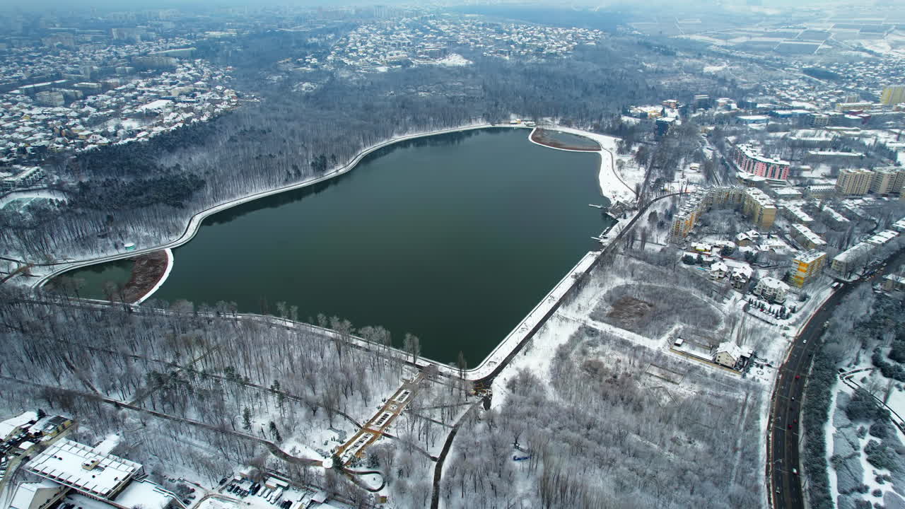 Vista aerea con drone di Chișinău in inverno, Moldavia. Vista del parco Valea Morilor con lago e alberi spogli, edifici intorno.