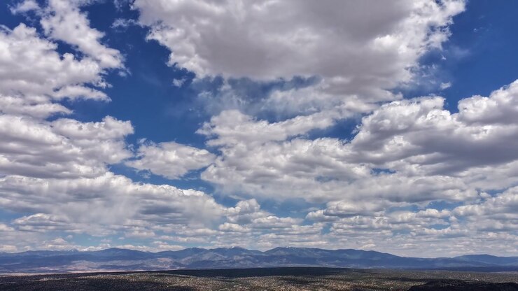 Timelapse 4K de dron captura capas de nubes con llovizna ligera que se desplazan hacia un horizonte montañoso distante. El movimiento aéreo cinematográfico revela cambios climáticos y virga sobre una vasta vista desértica del suroeste