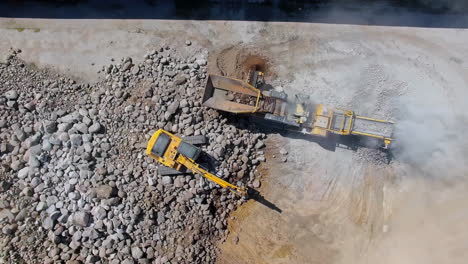 excavator and stone crusher at work in quarry site on a sunny day