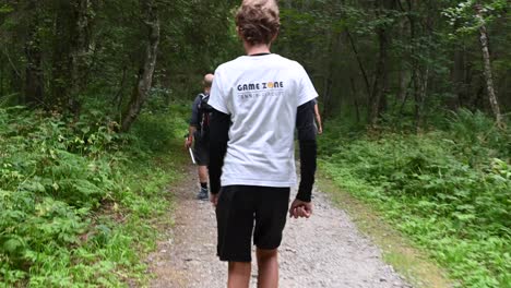 Hyperlapse:-a-teenager-is-walking-on-a-gravel-path-in-a-swiss-alps-forest-with-his-family,-Obwalden,-Engelberg