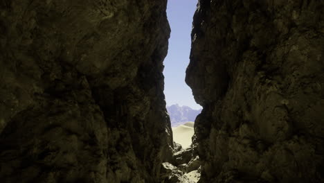 rugged rock formations lead to a serene sand dune landscape in daytime