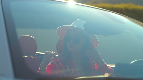 una mujer conduciendo un descapotable.