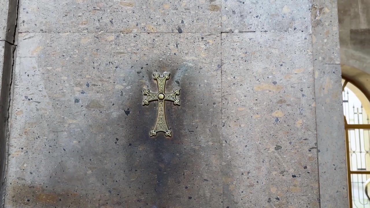 Croce sacra dorata montata su parete di granito nel design degli interni di una chiesa a Yerevan, Armenia, con patina di impronte toccate, simbolo di culto, preghiera, devozione, fede, cristianesimo, rito, pellegrinaggio, patrimonio e riverenza in Iran.