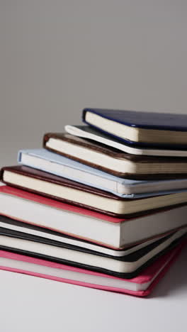 vertical video of stack of books with copy space on grey background, in slow motion