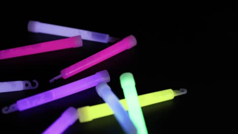 palos de brillo coloridos cayendo contra un fondo oscuro