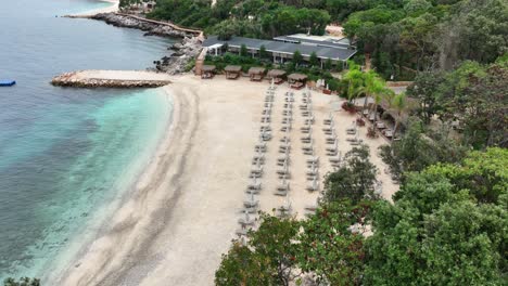 drone view of an empty private beach on the coast of albania full of beach loungers.