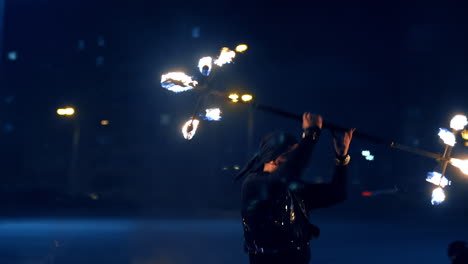male performer turning the burning stick over his head. fire spectacle outdoors at night.