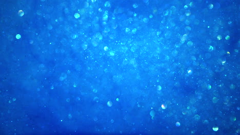 fondo de partículas brillantes azul brillante abstracto con luces bokeh y cristales congelados brillantes en bucle de agua